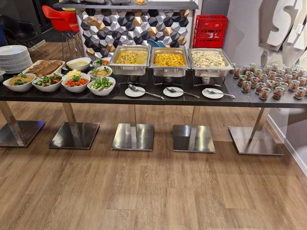Das Buffet am Freitagabend. Man sieht einen Tisch auf dem Links Salate und Brot, in der Mitte Curry, Gnocci und Reis und Links Schoko-Desserts aufgebaut sind.
